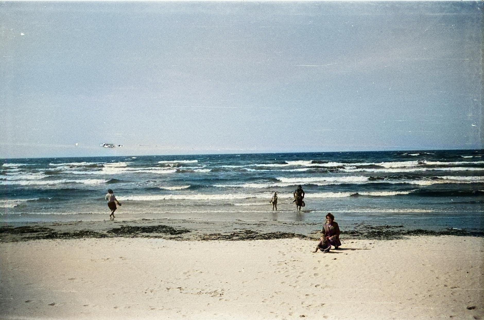 Rodzina spaceruje brzegiem morza na spokojnej plaży w Ventspils