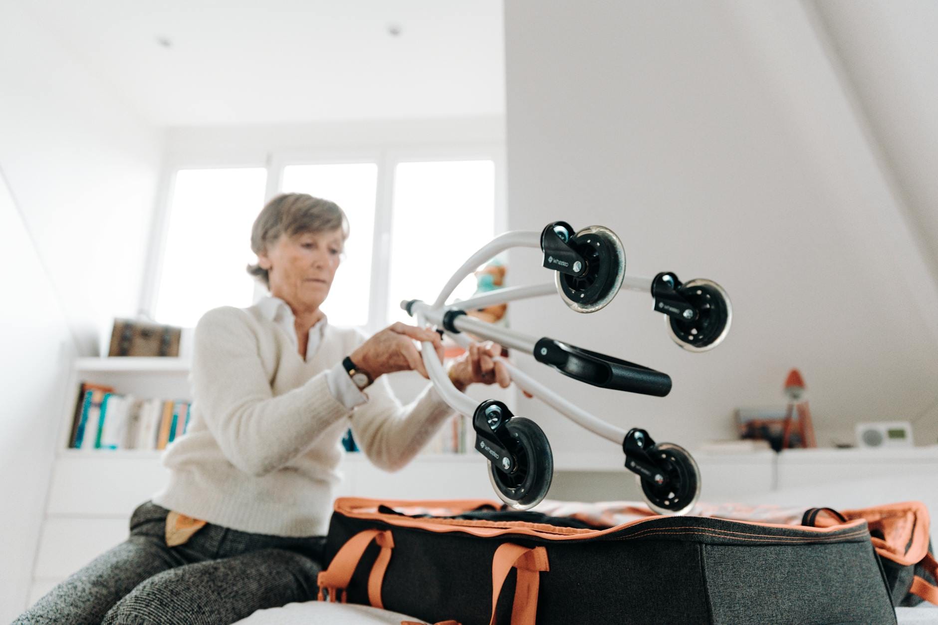 Starsza kobieta pakuje balkonika do walizki w jasnym pokoju