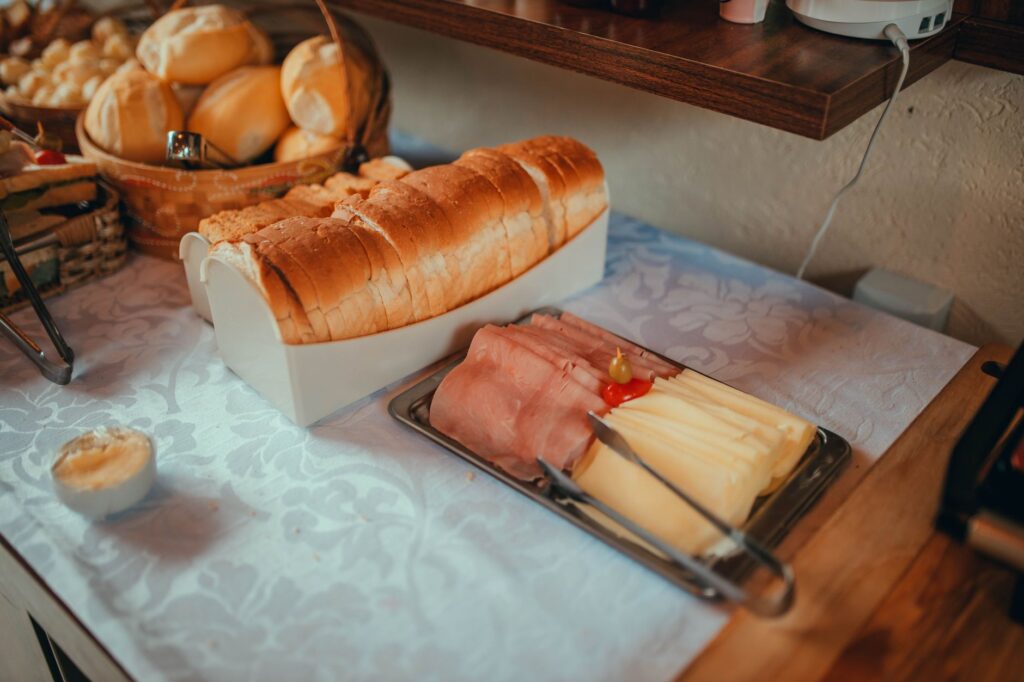 Pieczywo, szynka i ser na stole nakrytym lnianym obrusem
